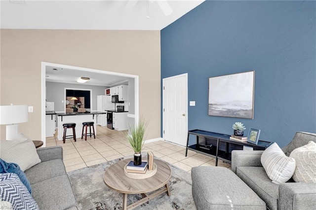 living room with light tile patterned floors, high vaulted ceiling, baseboards, and a ceiling fan