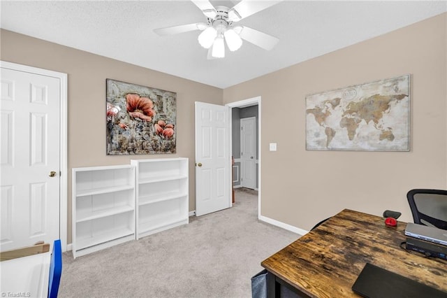 carpeted home office with a textured ceiling, baseboards, and a ceiling fan