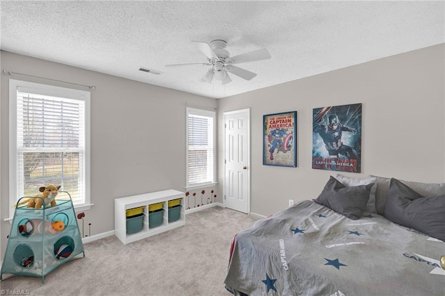 carpeted bedroom featuring a ceiling fan, baseboards, visible vents, and a textured ceiling