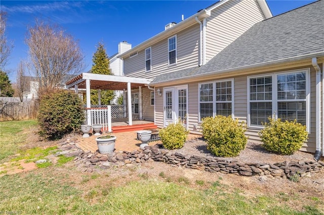 back of house with a pergola, fence, a shingled roof, a chimney, and a patio area