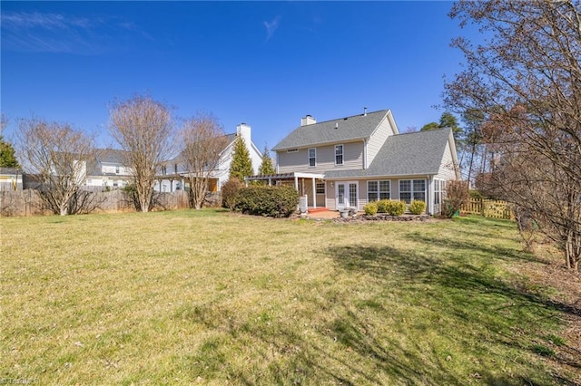 rear view of house featuring a yard, a patio, a chimney, and fence