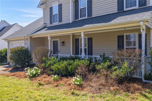 doorway to property with a porch, a shingled roof, and a garage