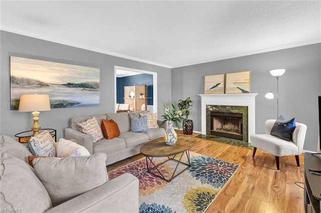 living area with a textured ceiling, a premium fireplace, wood finished floors, and ornamental molding