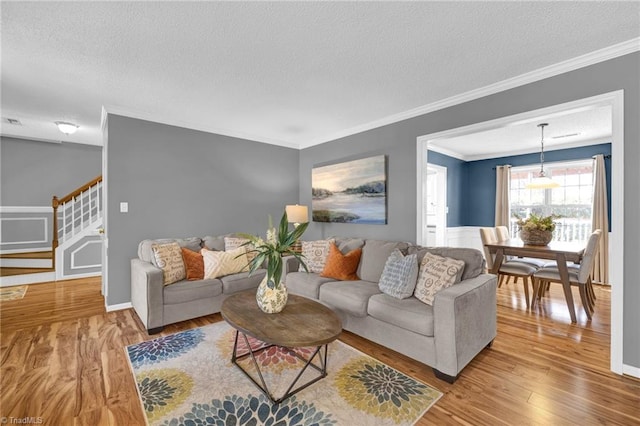 living room with stairway, a textured ceiling, crown molding, and wood finished floors