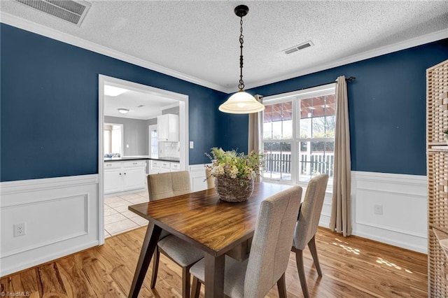 dining room featuring visible vents, wainscoting, and light wood-style floors