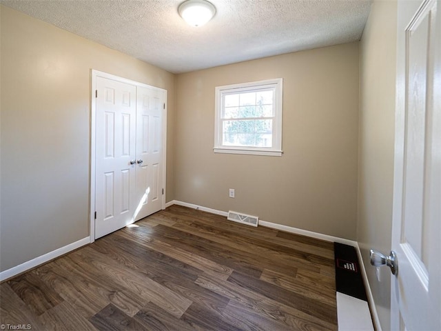 unfurnished bedroom with a closet, dark wood-type flooring, and a textured ceiling