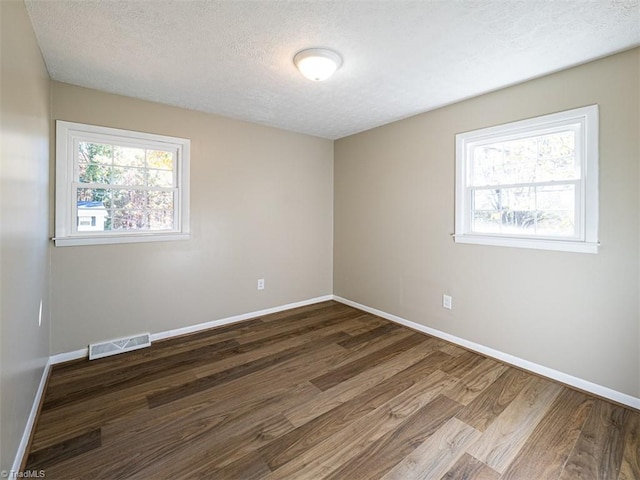 spare room with dark hardwood / wood-style floors and a textured ceiling