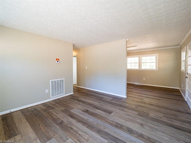 spare room with a textured ceiling, dark hardwood / wood-style flooring, and crown molding