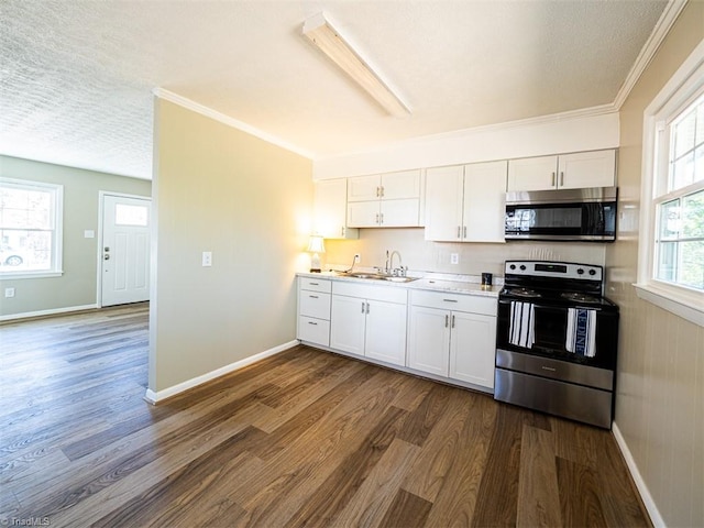 kitchen with appliances with stainless steel finishes, crown molding, sink, white cabinets, and dark hardwood / wood-style floors