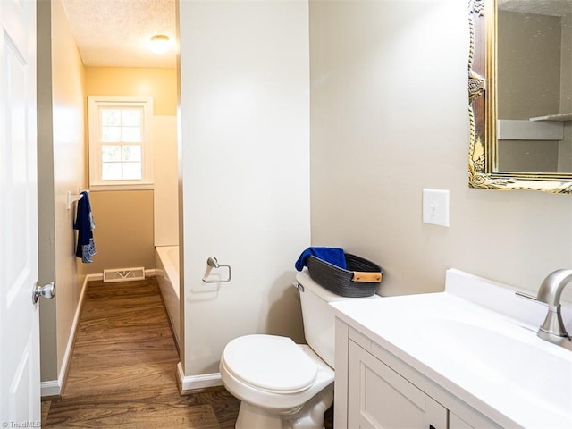 bathroom with a textured ceiling, vanity, hardwood / wood-style flooring, and toilet