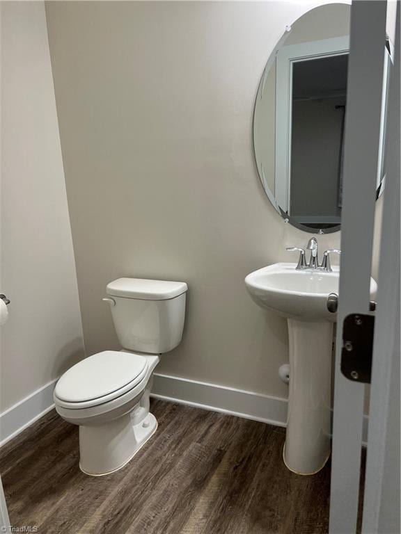 bathroom with toilet, wood finished floors, and baseboards