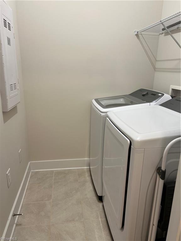 washroom with laundry area, washing machine and dryer, and baseboards