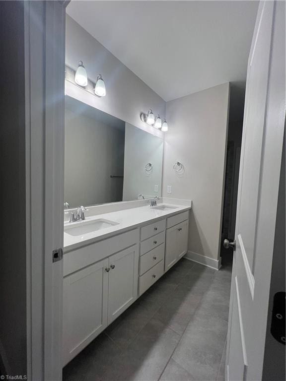 full bathroom featuring double vanity, baseboards, and a sink