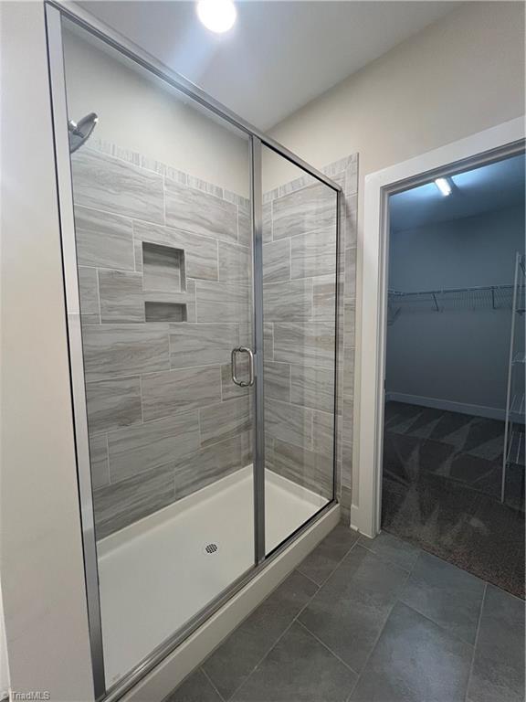 bathroom with a walk in closet and a stall shower