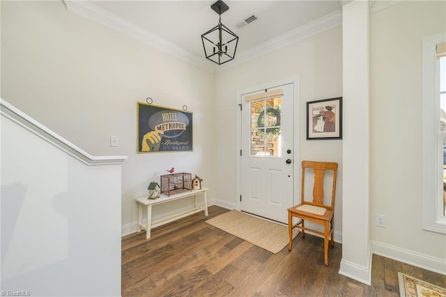 entrance foyer with dark wood-type flooring, crown molding, and a notable chandelier