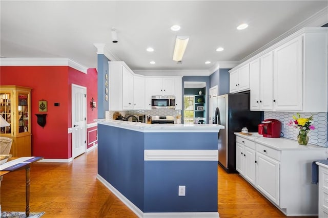 kitchen featuring stainless steel appliances, light countertops, light wood-style flooring, white cabinetry, and ornamental molding