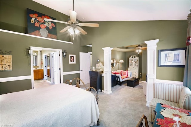 bedroom with decorative columns, light colored carpet, high vaulted ceiling, ceiling fan, and connected bathroom