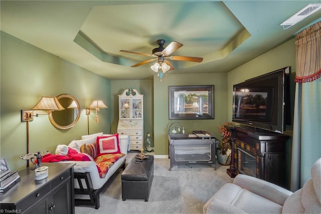living area with carpet, ceiling fan, a raised ceiling, and baseboards