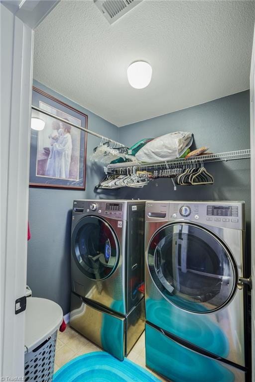 laundry area featuring washer and dryer, a textured ceiling, and tile patterned flooring