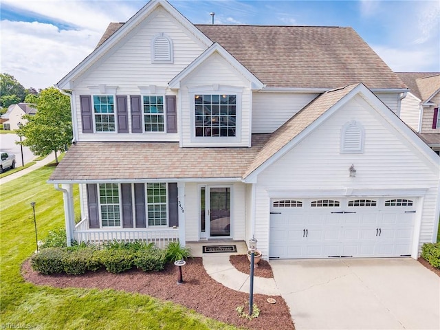 traditional-style home with a porch, concrete driveway, a shingled roof, a garage, and a front yard