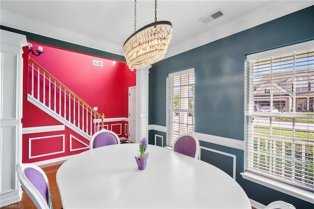 dining space with a chandelier, a wainscoted wall, and crown molding