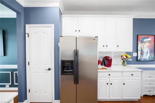 kitchen featuring stainless steel refrigerator with ice dispenser, white cabinetry, crown molding, light countertops, and backsplash