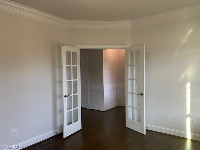 spare room featuring dark wood-style flooring, french doors, baseboards, and ornamental molding