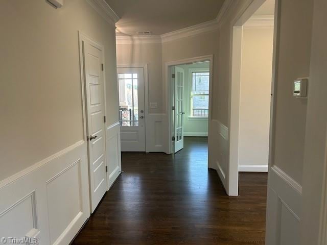 hall with a decorative wall, dark wood-type flooring, wainscoting, and ornamental molding