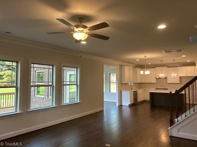 unfurnished living room with baseboards, dark wood-style flooring, ornamental molding, a ceiling fan, and stairway