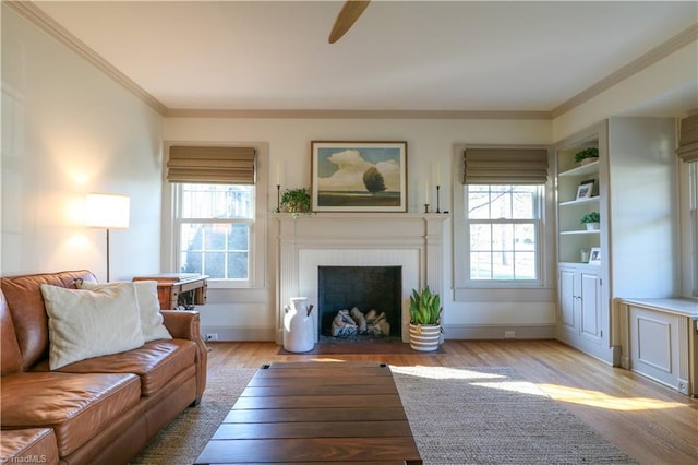 living area with a fireplace, baseboards, crown molding, and light wood-style floors