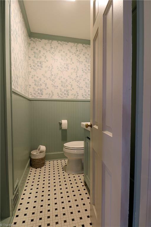 bathroom featuring toilet, wallpapered walls, crown molding, wainscoting, and vanity