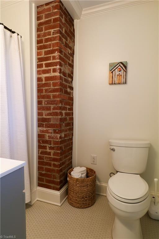 full bathroom with vanity, baseboards, ornamental molding, curtained shower, and toilet