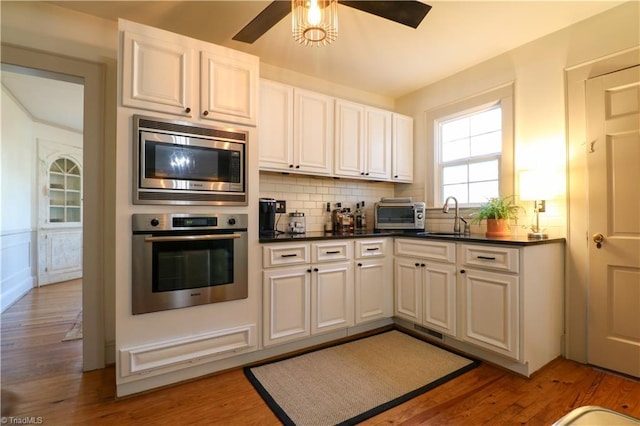 kitchen with a sink, decorative backsplash, light wood-type flooring, and stainless steel appliances