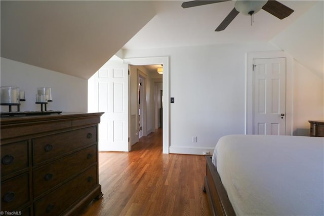 bedroom featuring lofted ceiling, wood finished floors, baseboards, and ceiling fan