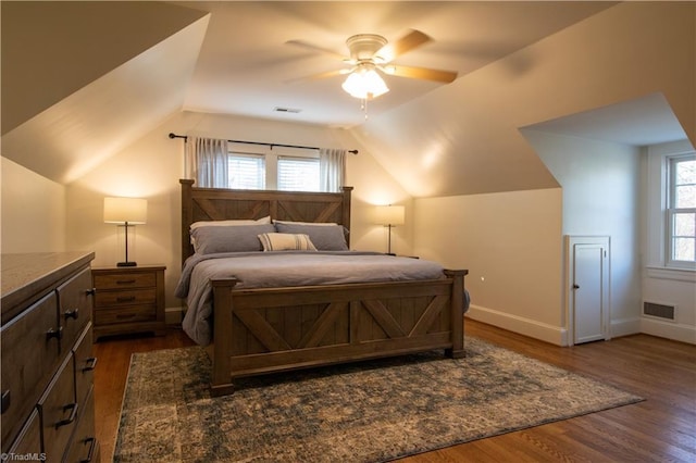 bedroom with visible vents, baseboards, vaulted ceiling, dark wood-style floors, and a ceiling fan