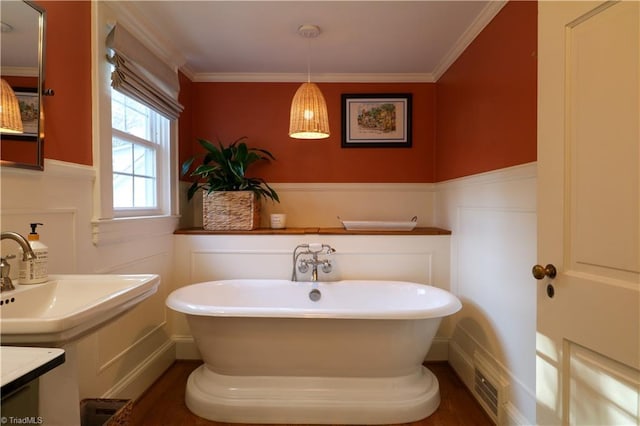 bathroom featuring a decorative wall, ornamental molding, a wainscoted wall, and a freestanding bath