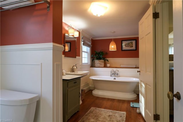 full bath with toilet, ornamental molding, a freestanding tub, wood finished floors, and vanity