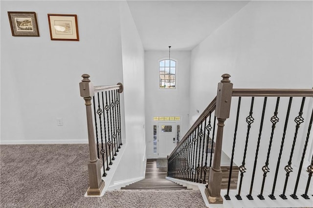 stairway with a chandelier and carpet flooring