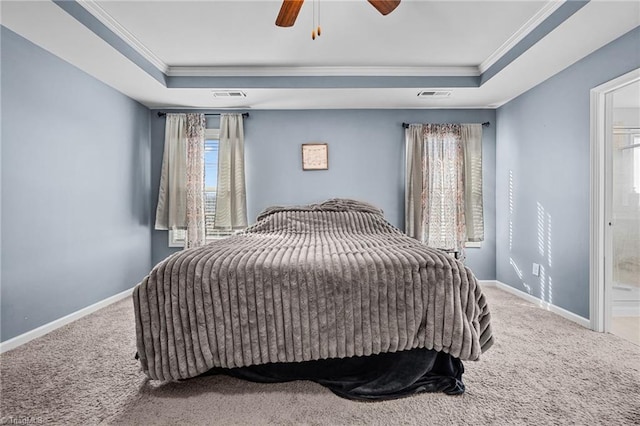 carpeted bedroom with ceiling fan, a tray ceiling, connected bathroom, and ornamental molding