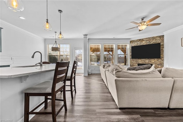 living room with a fireplace, sink, dark hardwood / wood-style floors, ornamental molding, and ceiling fan