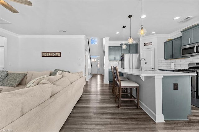 kitchen featuring pendant lighting, a kitchen bar, stainless steel appliances, an island with sink, and sink