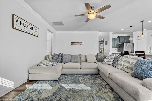 living room featuring ceiling fan, dark wood-type flooring, sink, and ornamental molding