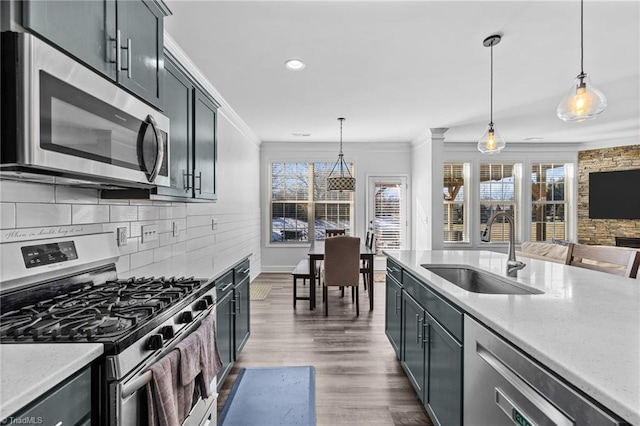 kitchen featuring appliances with stainless steel finishes, decorative light fixtures, decorative backsplash, sink, and crown molding