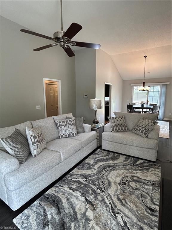 2 Whispering Ct, Greensboro, NC 27407 - living area with lofted ceiling, a ceiling fan, wood finished floors, and a chandelier