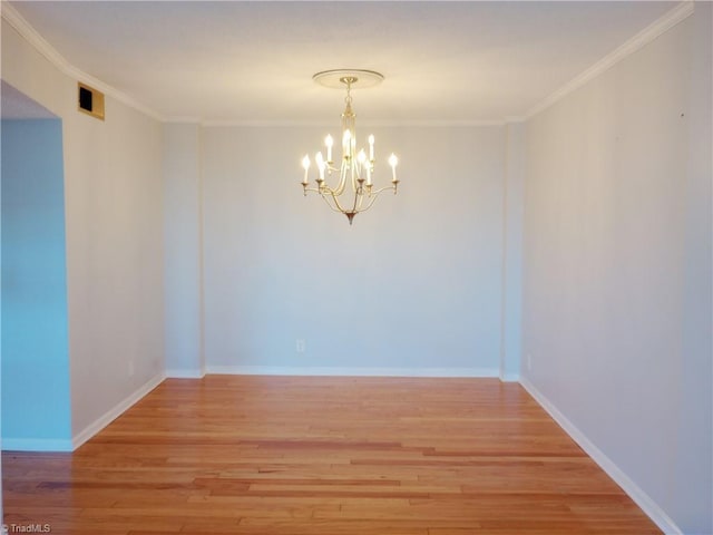 empty room featuring light hardwood / wood-style flooring, crown molding, and a chandelier