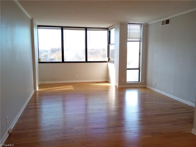 empty room with crown molding and light wood-type flooring