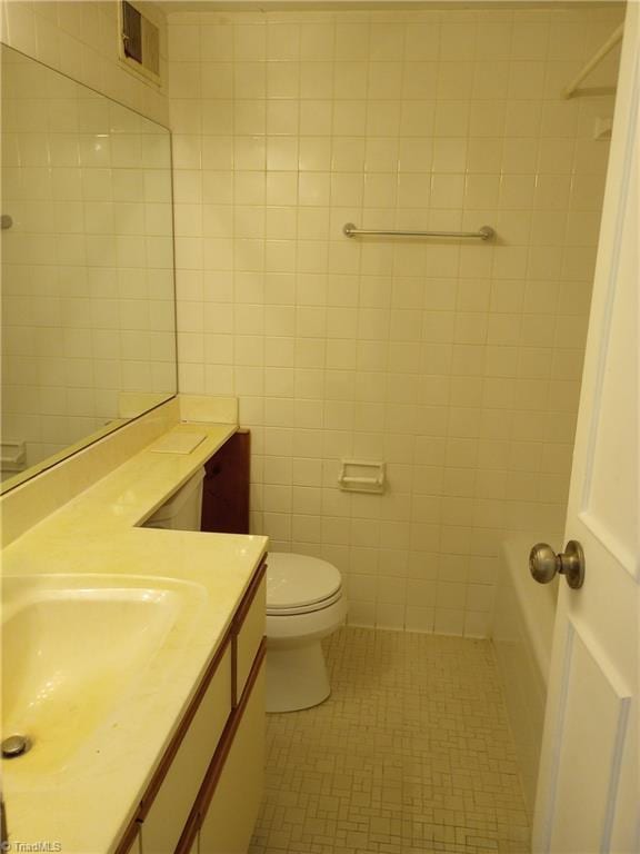 bathroom featuring tile patterned floors, vanity, tile walls, and toilet