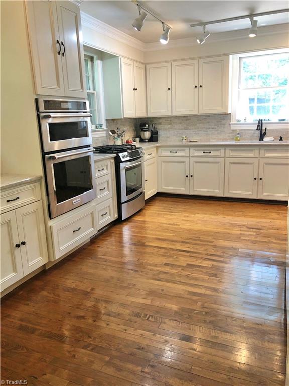 kitchen with appliances with stainless steel finishes, light hardwood / wood-style floors, white cabinetry, and sink