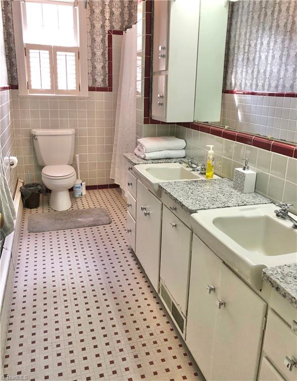 bathroom featuring tile walls, curtained shower, vanity, tile patterned flooring, and toilet