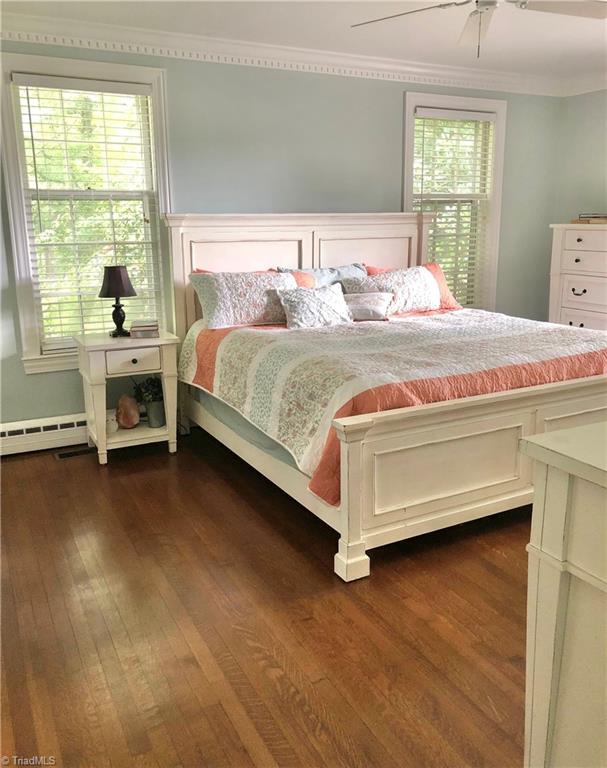 bedroom featuring ceiling fan, crown molding, dark hardwood / wood-style floors, and multiple windows